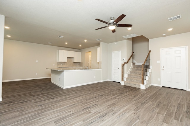 unfurnished living room featuring stairs, a ceiling fan, baseboards, wood finished floors, and visible vents