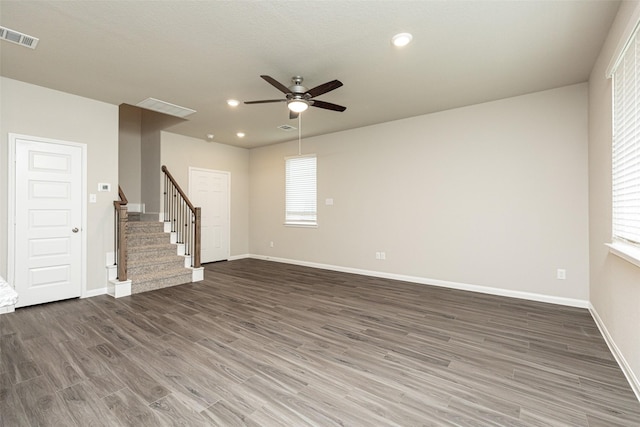 unfurnished living room featuring visible vents, wood finished floors, baseboards, stairway, and a ceiling fan