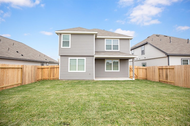 back of house featuring a lawn, roof with shingles, a fenced backyard, and a patio area