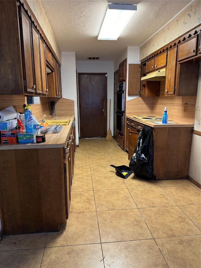335 Haymarket Ln, Houston, TX 77015 - kitchen with dobule oven black, dark brown cabinetry, a textured ceiling, visible vents, and under cabinet range hood