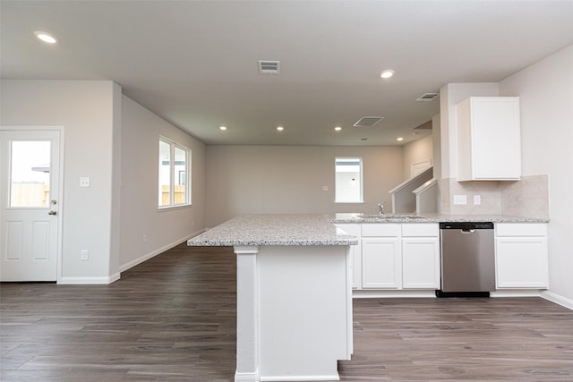 kitchen with stainless steel dishwasher, white cabinetry, visible vents, and wood finished floors