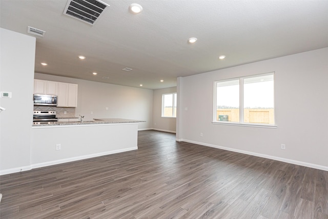 unfurnished living room featuring recessed lighting, baseboards, dark wood finished floors, and visible vents
