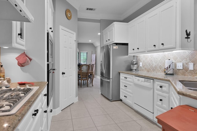 5 Highland Hollow Dr, Conroe, TX 77304 - kitchen with stainless steel appliances, light tile patterned floors, white cabinetry, tasteful backsplash, and ornamental molding
