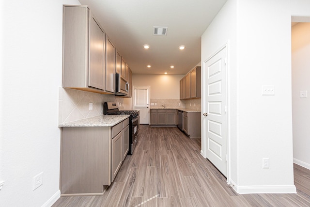 13609 Goldeye Dr, Conroe, TX 77384 - kitchen featuring appliances with stainless steel finishes, decorative backsplash, visible vents, and light wood-type flooring