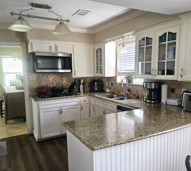 kitchen featuring a sink, stainless steel microwave, black gas stovetop, and a healthy amount of sunlight