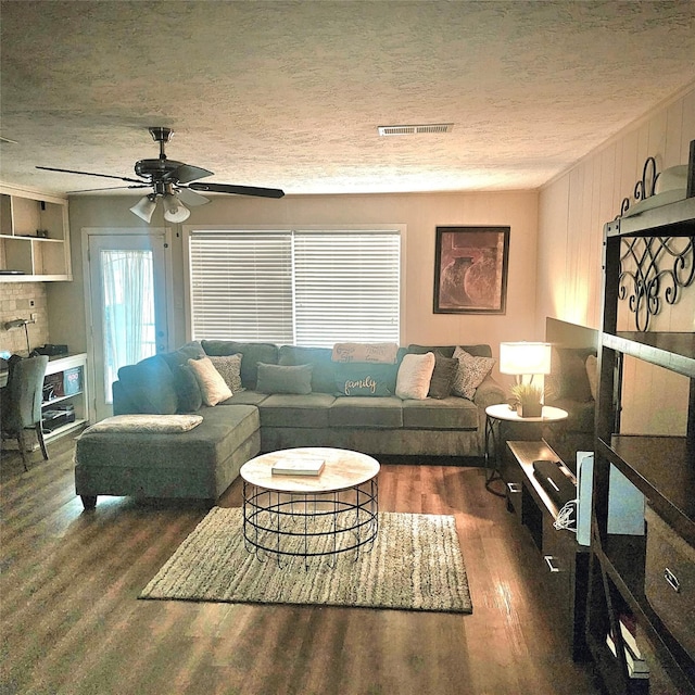 living room featuring a textured ceiling, a ceiling fan, wood finished floors, and visible vents