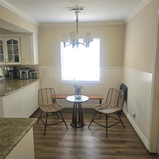 dining room with visible vents, crown molding, wainscoting, dark wood-style floors, and a notable chandelier