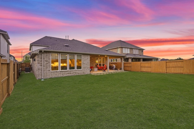 720 Serenity View Ln, Katy, TX 77493 - back of house at dusk featuring brick siding, a shingled roof, a fenced backyard, and a patio area