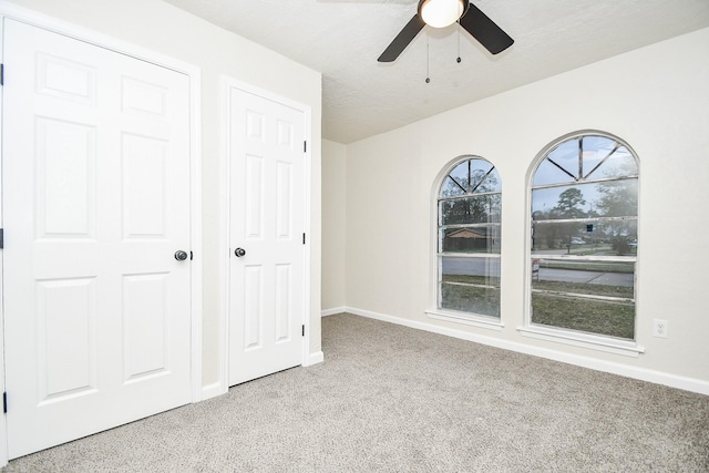 unfurnished bedroom featuring a ceiling fan, baseboards, and carpet