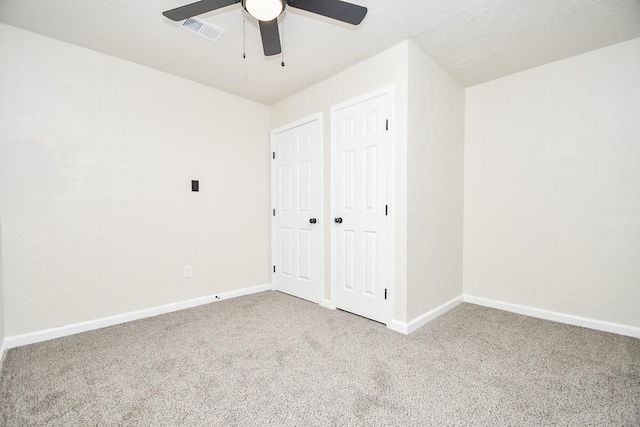 unfurnished bedroom featuring carpet floors, visible vents, a closet, baseboards, and a ceiling fan