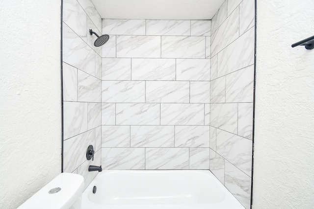 full bath with toilet, a textured wall, and shower / tub combination
