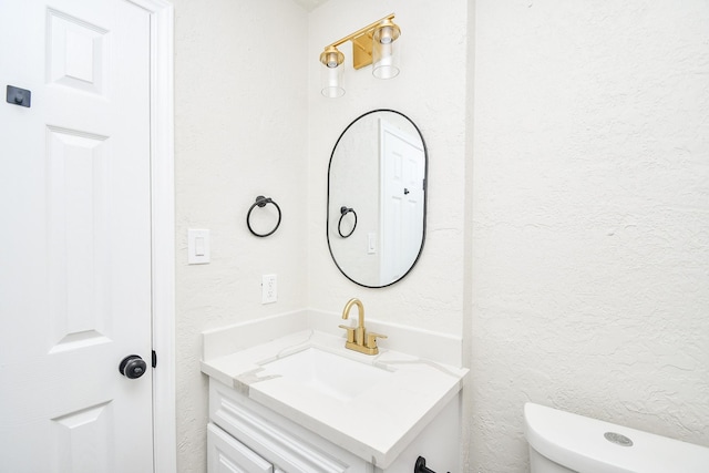 bathroom with vanity, a textured wall, and toilet