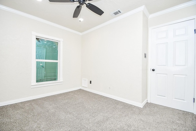 spare room featuring carpet floors, a ceiling fan, visible vents, and ornamental molding