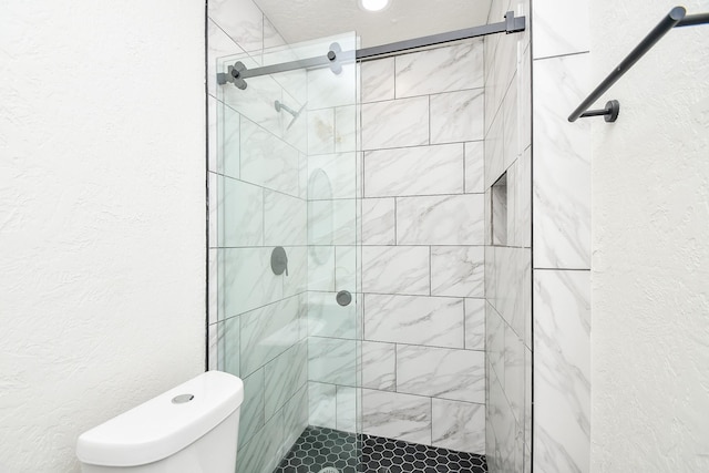 bathroom with a textured wall, a stall shower, and toilet