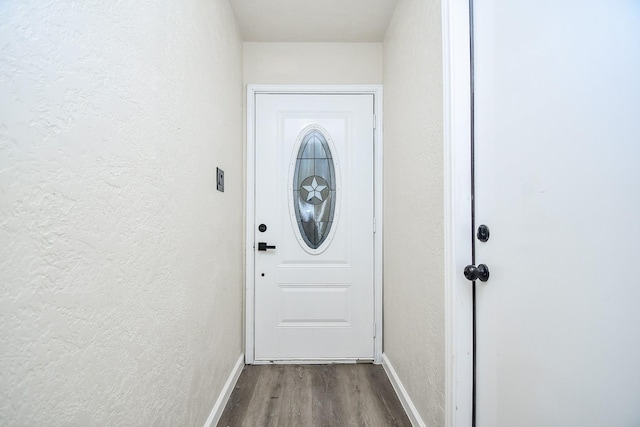 doorway to outside featuring baseboards, a textured wall, and wood finished floors