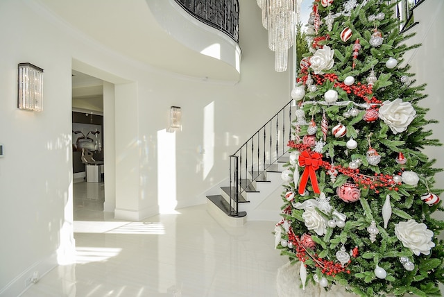 foyer with tile patterned floors, baseboards, a chandelier, ornamental molding, and stairs