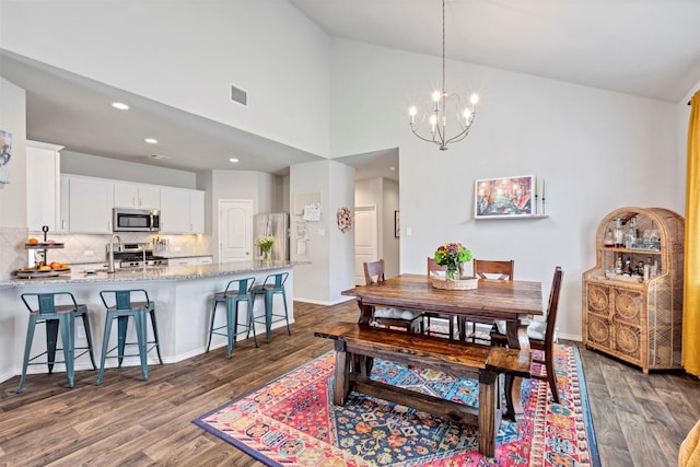 dining space with dark wood-style flooring, a chandelier, recessed lighting, high vaulted ceiling, and baseboards