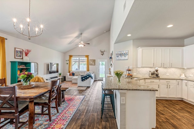 kitchen with a peninsula, light stone counters, white cabinets, backsplash, and recessed lighting