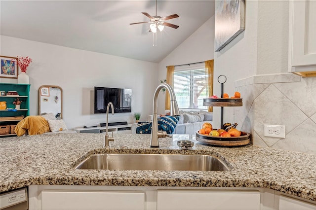 kitchen featuring open floor plan, a sink, white cabinets, light stone countertops, and vaulted ceiling