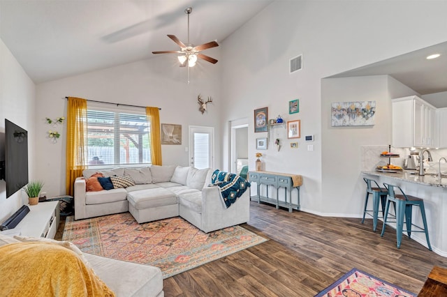 living area featuring a ceiling fan, dark wood finished floors, high vaulted ceiling, and baseboards