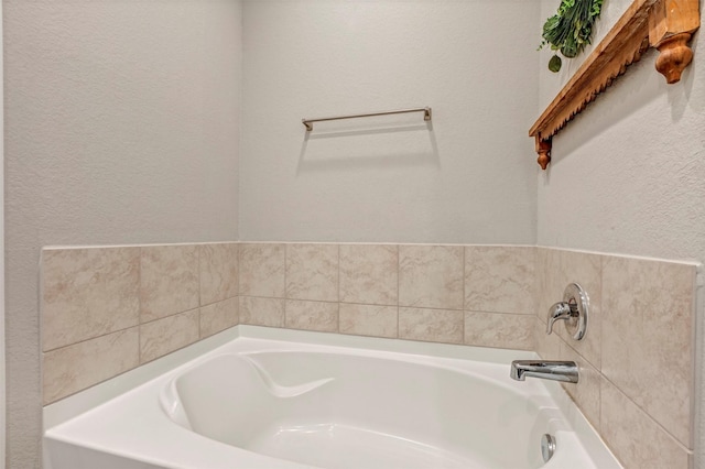 bathroom featuring a bath and a textured wall