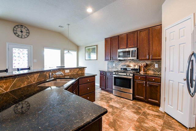 kitchen featuring a sink, visible vents, stainless steel appliances, backsplash, and vaulted ceiling
