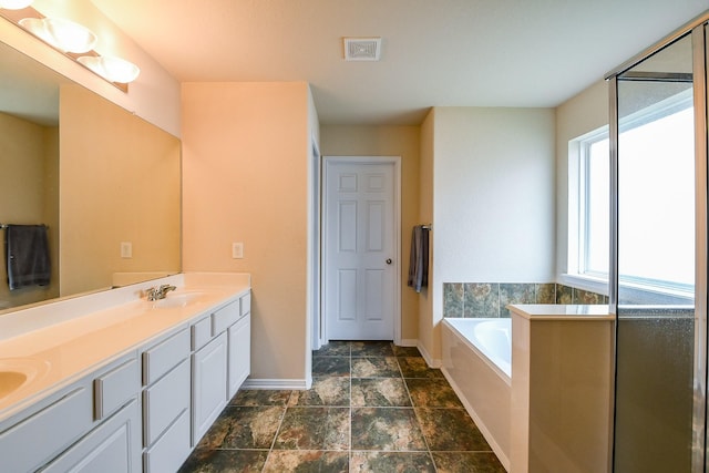 bathroom featuring a sink, double vanity, baseboards, visible vents, and a garden tub