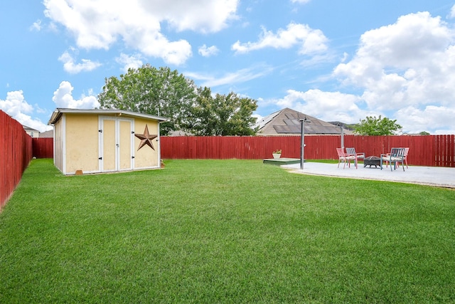 view of yard featuring a storage unit, an outdoor fire pit, a fenced backyard, an outbuilding, and a patio area