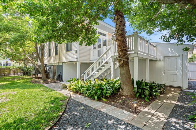 view of side of home featuring a lawn, a deck, fence, and stairs
