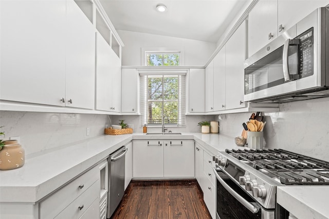 kitchen with a sink, light countertops, stainless steel appliances, decorative backsplash, and dark wood-style floors