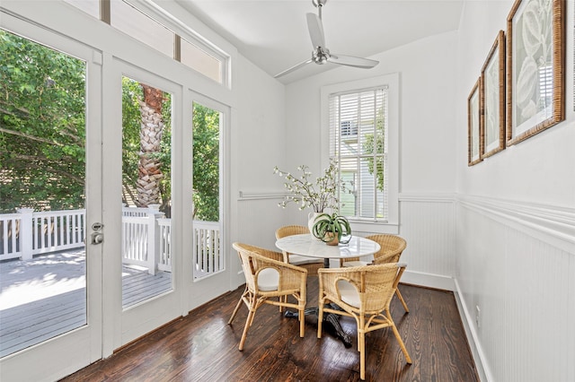 dining area with a decorative wall, a wainscoted wall, a ceiling fan, lofted ceiling, and dark wood-style floors