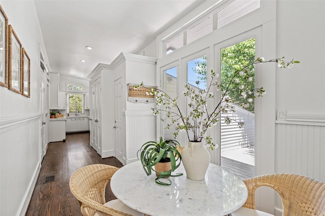 dining area with a decorative wall, dark wood-type flooring, and visible vents