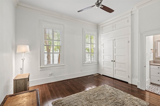 unfurnished bedroom with crown molding, a ceiling fan, baseboards, dark wood-style floors, and a closet