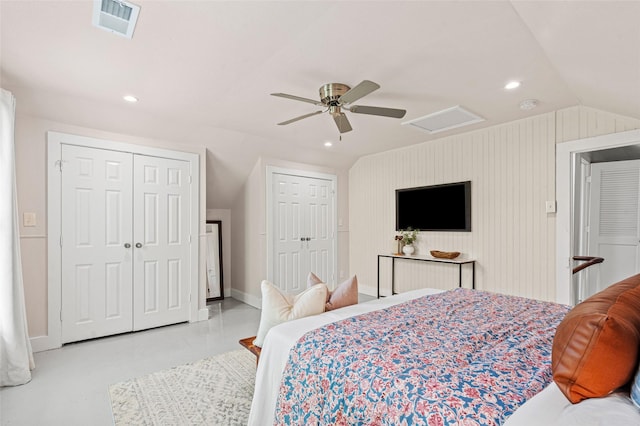 bedroom featuring visible vents, lofted ceiling, two closets, attic access, and a ceiling fan