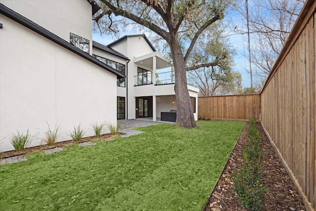 view of yard featuring a balcony, a fenced backyard, and a patio area