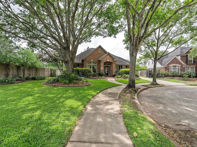 view of front of house with brick siding, fence, and a front lawn