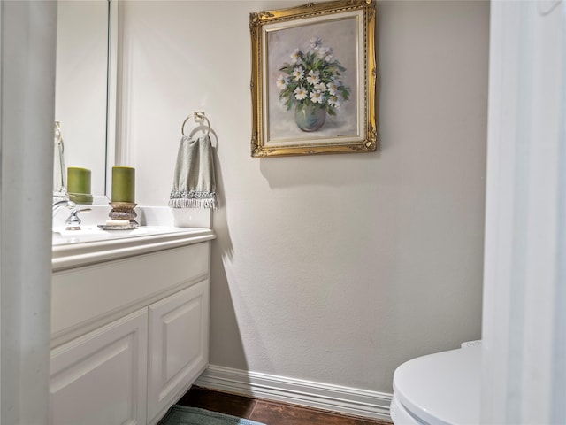 half bathroom with toilet, baseboards, and vanity