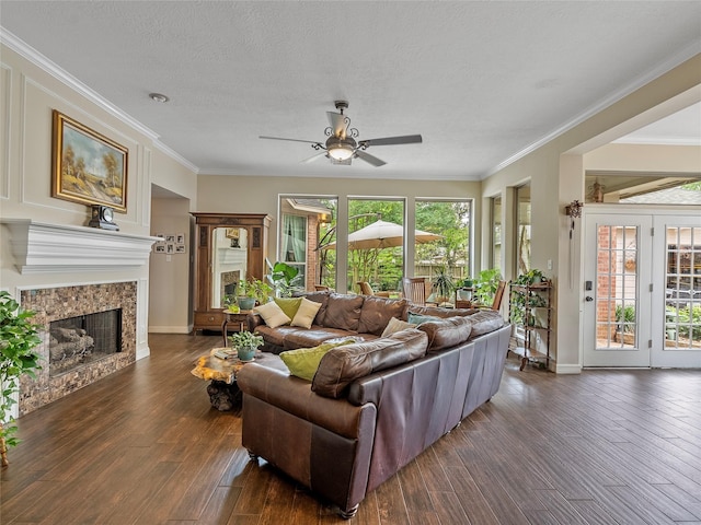 living room with crown molding, wood-type flooring, a ceiling fan, and a fireplace