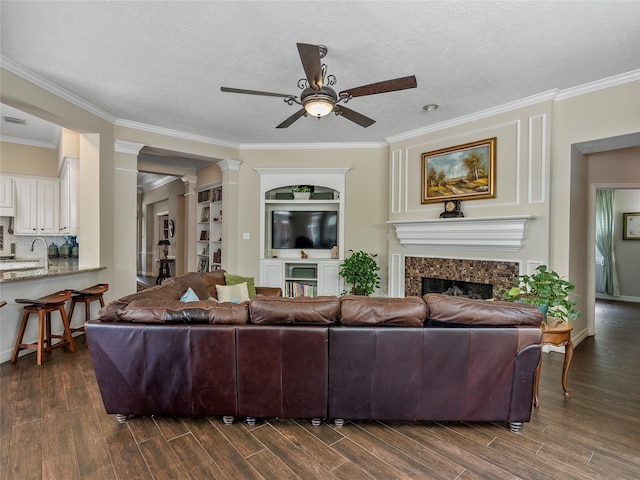 living room with crown molding, a ceiling fan, dark wood-style floors, and a premium fireplace