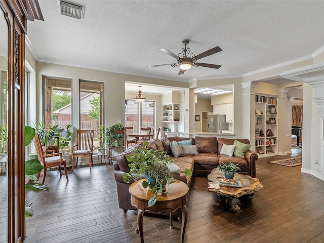 living area with ornate columns, a ceiling fan, a textured ceiling, and visible vents