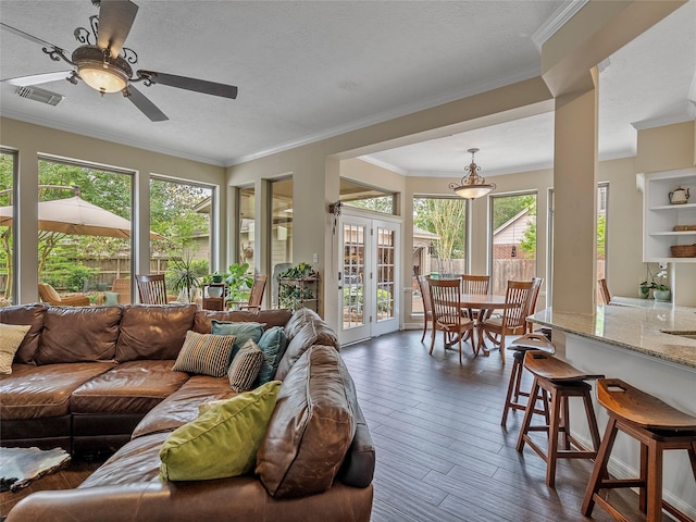 living area with ceiling fan, ornamental molding, a wealth of natural light, and dark wood-type flooring