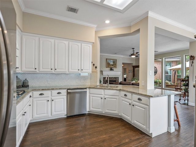 kitchen with visible vents, a fireplace, ceiling fan, a sink, and appliances with stainless steel finishes