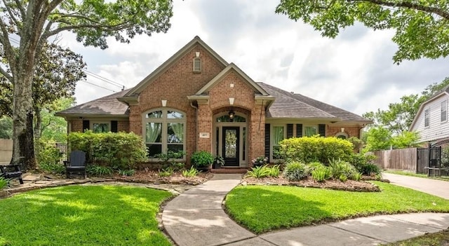 view of front of home featuring brick siding, fence, and a front lawn