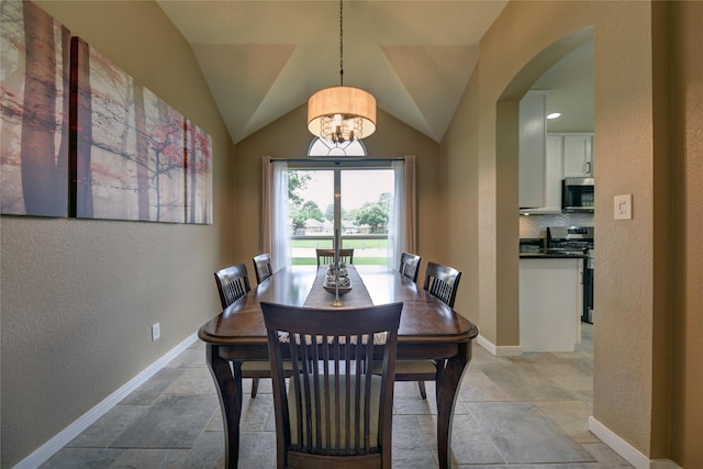 dining room with stone tile floors, a textured wall, baseboards, arched walkways, and a notable chandelier