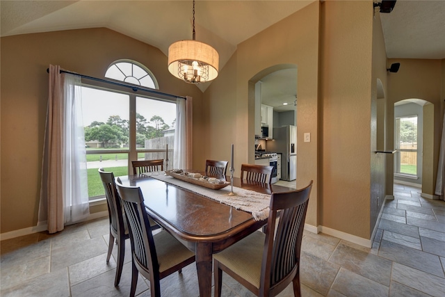dining area with arched walkways, baseboards, and stone tile flooring