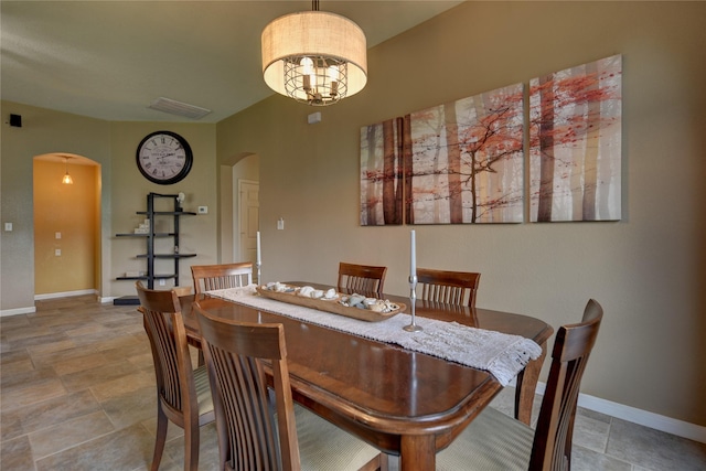 dining room with arched walkways, a chandelier, stone finish floor, baseboards, and visible vents