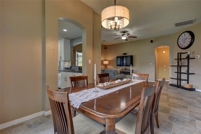 dining room with visible vents, baseboards, ceiling fan, arched walkways, and stone finish flooring