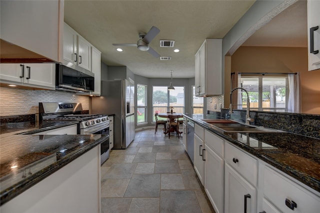 kitchen with white cabinets, a sink, stainless steel appliances, a ceiling fan, and visible vents