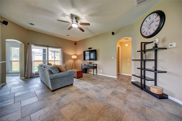 living area featuring arched walkways, ceiling fan, and visible vents