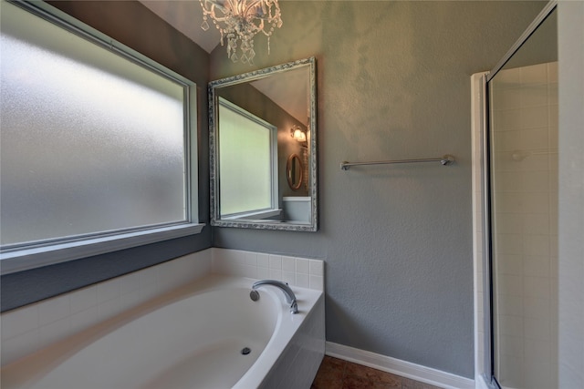 bathroom featuring a healthy amount of sunlight, tile patterned flooring, a bath, and a chandelier